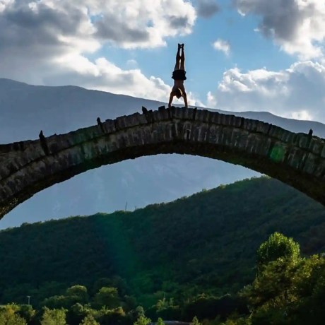 a person does a handstand on a bridge