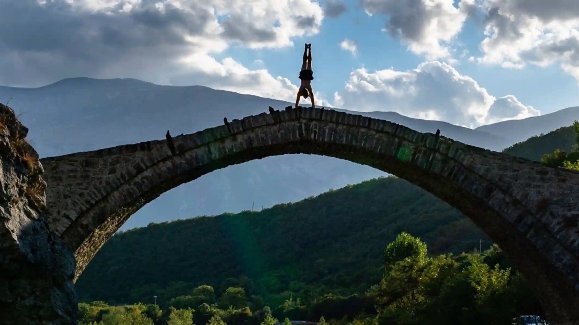 a person does a handstand on a bridge