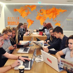 a group of people sitting at a table with laptops