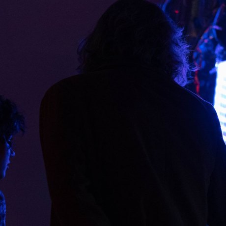 a person in a really dark room facing a colorful beamer presentation