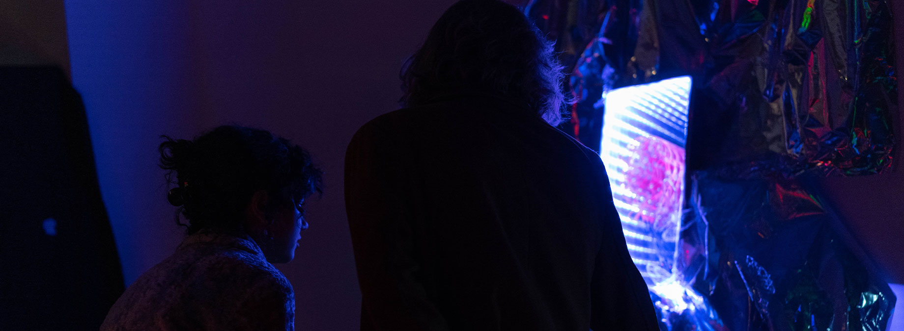 a person in a really dark room facing a colorful beamer presentation