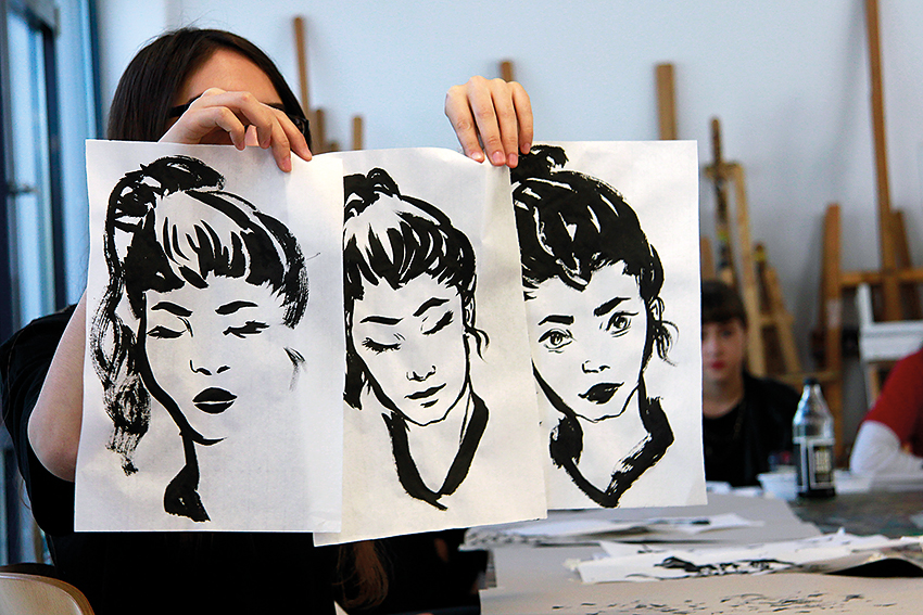 Woman holding up three artworks in front of her