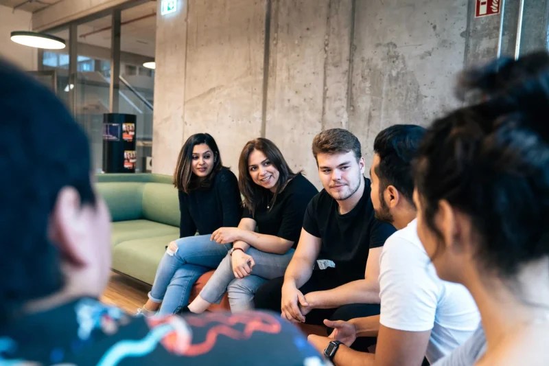 six people sitting on a sofa and chatting