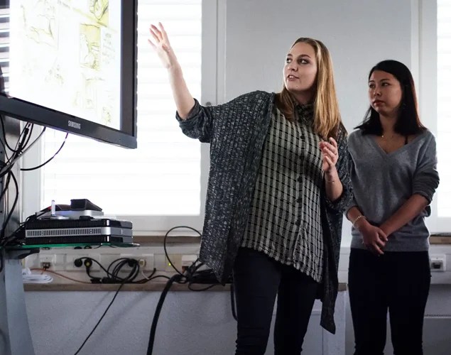 two girls are presenting something on a screen