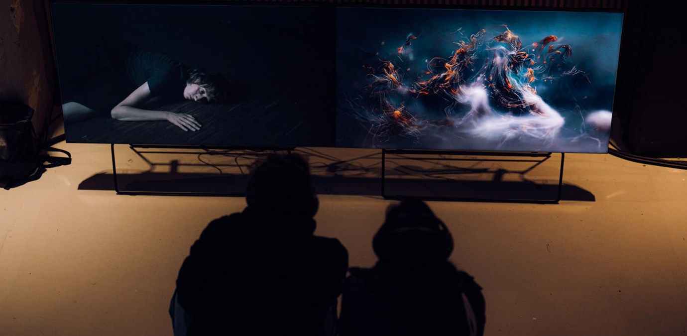 two people sitting in front of screens and watching movies