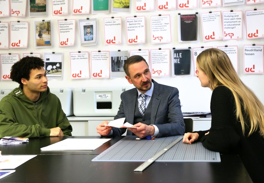 three people sitting at a desk discussing something