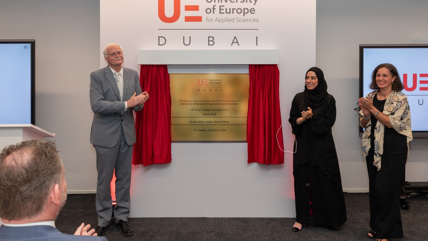 One man and two women unveil plaque on a wall
