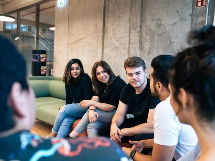 six people sitting on a sofa and chatting