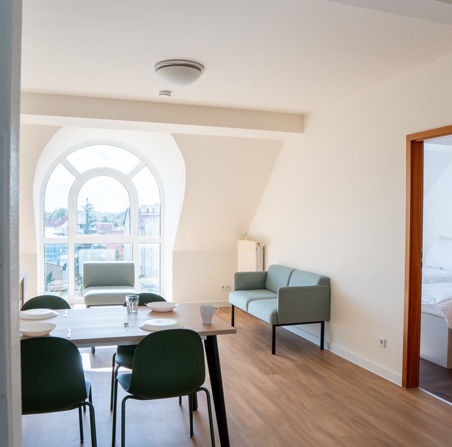 a student room with a table chairs and a window