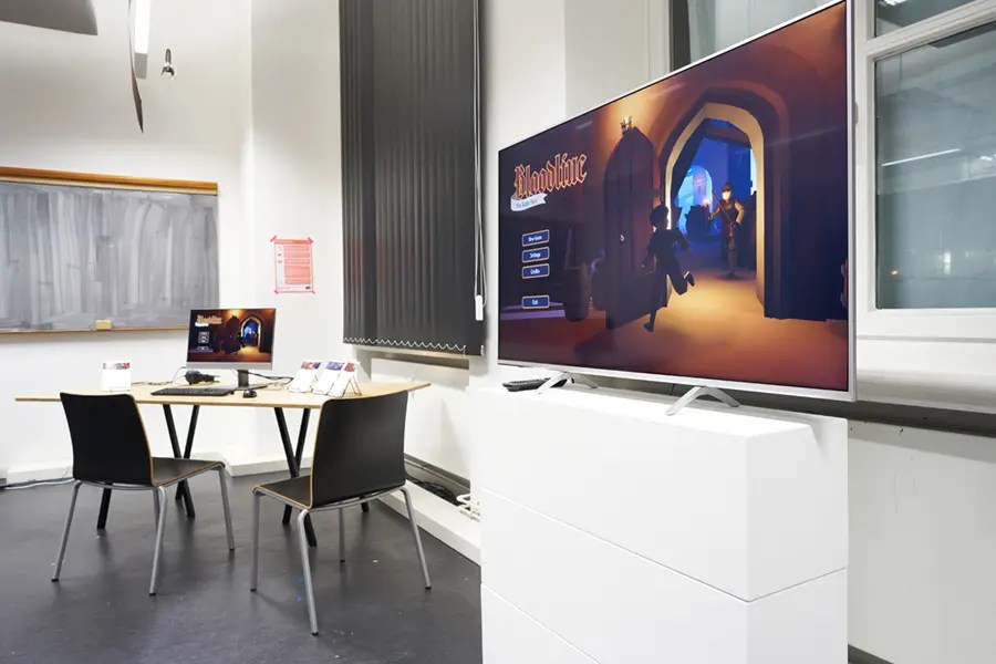 Ein Raum mit einem Computer und einem Fernsehbildschirm, auf dem ein Spiel angezeigt wird