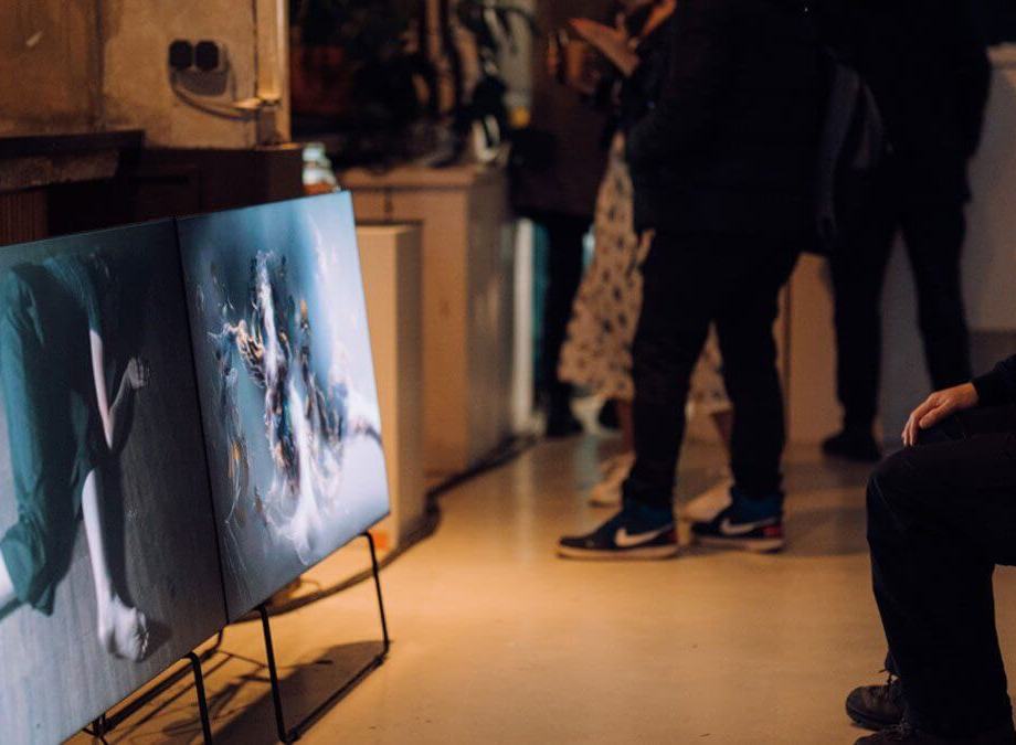 Eine Person sitzt und betrachtet ein digitales Kunstwerk