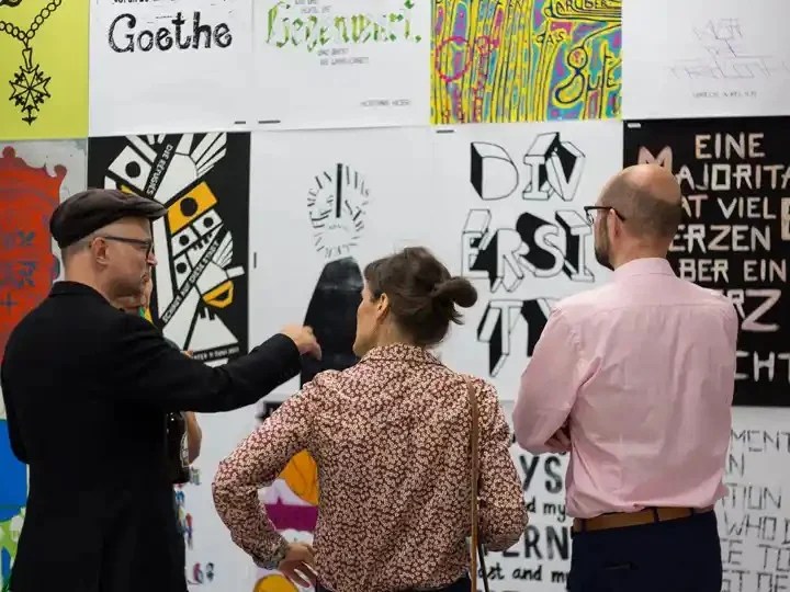 drei Personen, die ein Kunstwerk an einer Wand betrachten