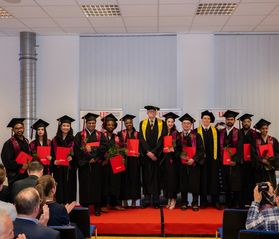 a group of people in graduation gowns standing on a red carpet