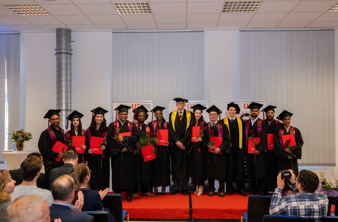 a group of people in graduation gowns standing on a red carpet