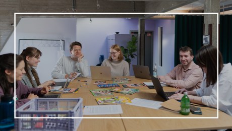 a group of people sitting around a table with laptops