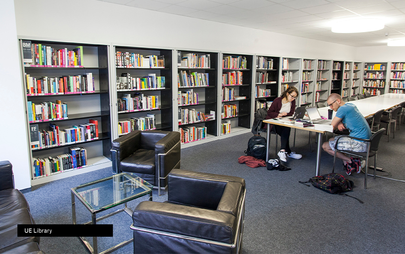 a man and woman sitting at a table in a library