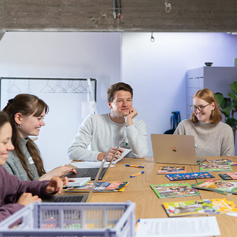 a group of people sitting at a table with laptops
