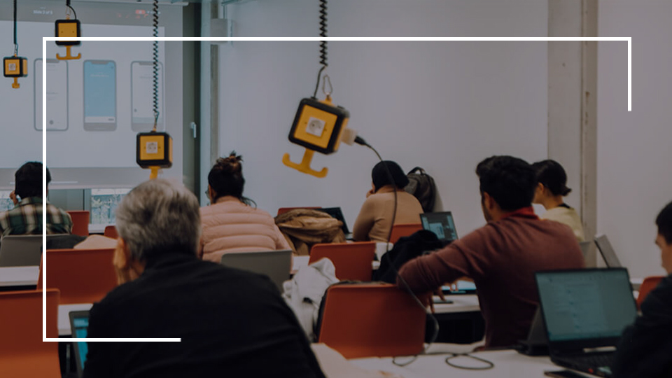 a group of people sitting in a room with laptops