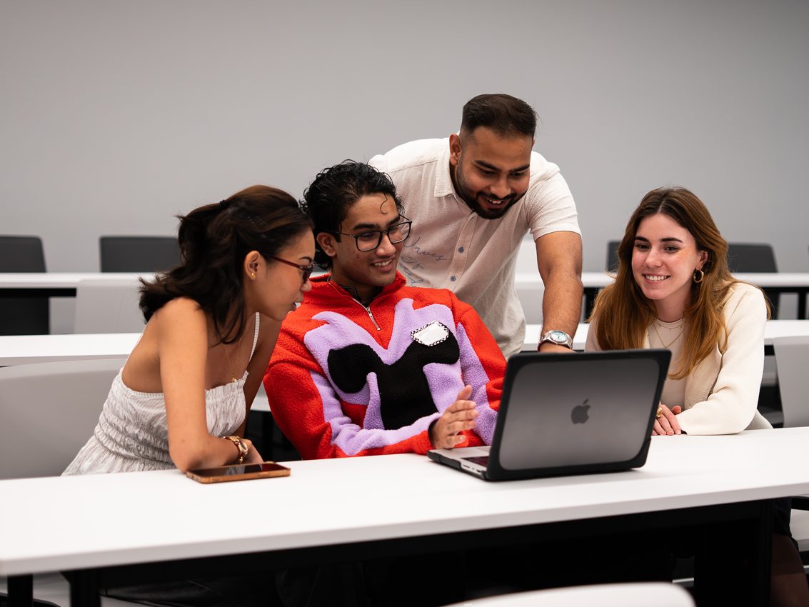 a group of people looking at a laptop